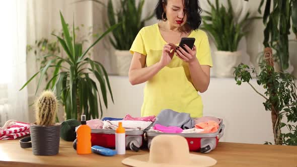 Travel Woman Packing Suitcase Check Things on the Smartphone