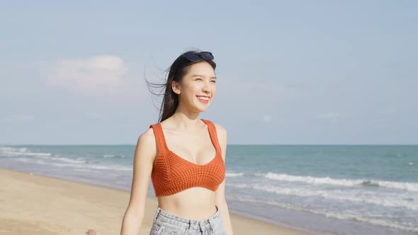 Asian young beautiful woman walking slowly on beach during summer time.