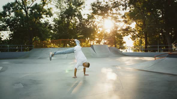 Young Man is Spinning Performing Windmill Movement While Breakdancing on Pump Track of Skatepark