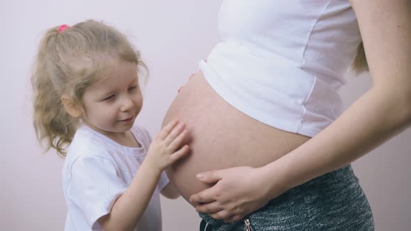 Girl Kisses Large Tummy of Pregnant Mummy Listening To Baby
