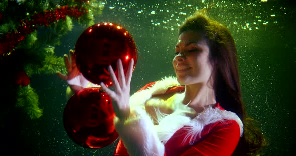 Portrait of a Bright Girl in a Christmas Red Suit, She Is Under Water, Next To Her Elegant Christmas