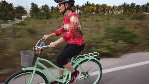 Closeup of mature woman riding a cruiser bike on a tropical vacation.