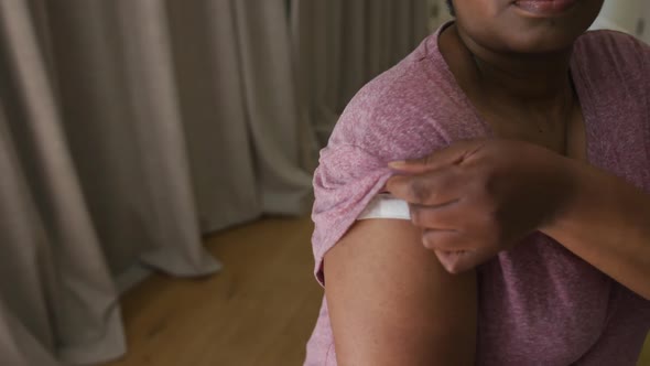 African american man showing plaster on arm where he was vaccinated against coronavirus