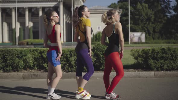 Wide Shot Side View of Cheerful 1980s Women in Sportswear and Sunglasses Dancing and Smiling at