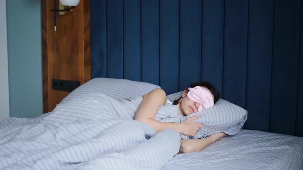 Woman in a Pink Eye Mask Lies Under a Blanket in a Bed and Suffers From Insomnia