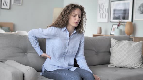 Curly Hair Woman with Spinal Back Pain Sitting on Couch