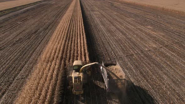 Aerial view of combine loading truck in cornfield