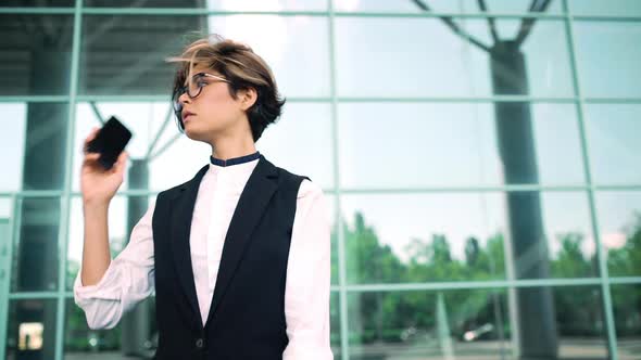 Young Beautiful Businesswoman Speaking on Phone Looking at Watch Business Centre Background