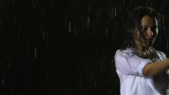 A Dancer in a Wet White Bodysuit and Shirt Is Dancing Salsa Elements in the Pouring Rain. Silhouette