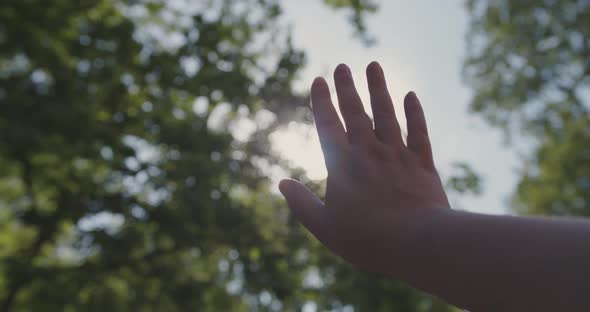 Caucasian Woman Closes the Sun with Her Hand in Slow Motion in the Park