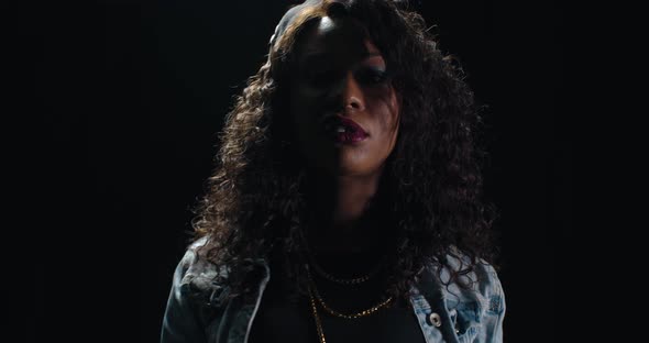 Beautiful Young Woman in Denim Jacket Is Posing in a Dark Room African American