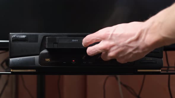 Hand of Man Inserting VHS Cassette in a Player