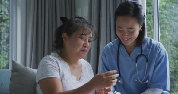 Smiling asian female doctor talking to happy female patient about her medication at hospital