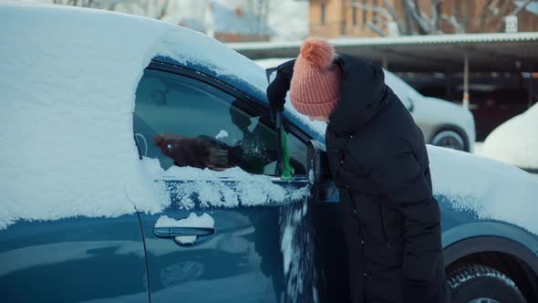 Sweep Snow From Automobile With Brushes In Winter. Scraping Ice. Scratching Ice From Car Window.