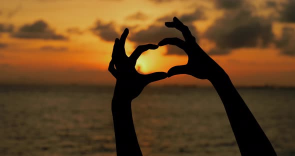 Woman finger showing heart shape over the sea