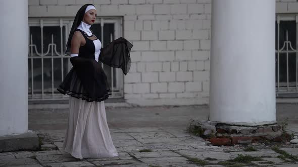 Sexy Lady is Wearing Erotic Suit of Catholic Nun Woman is Walking Near Old Monastery