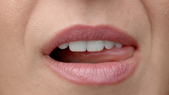 Woman Licks Her Lips Close Up. Gentle Female Tongue Licks Beautiful White Teeth
