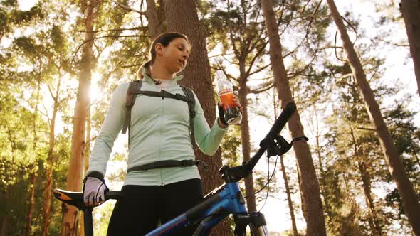 Female mountain biker drinking water in the forest