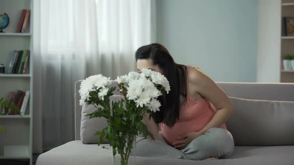 Expectant Mother Admiring Beautiful Bouquet of Flowers Presented by Husband