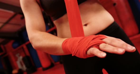 Female boxer wearing red strap on wrist in fitness studio