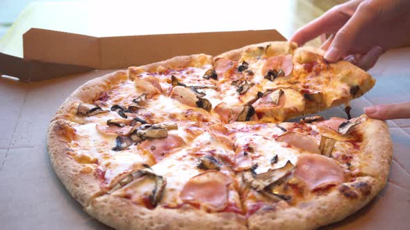 Woman Hand Takes a Slice of Hot Pizza with Stretching Cheese Fluffy Pizza with Ham Mushrooms and