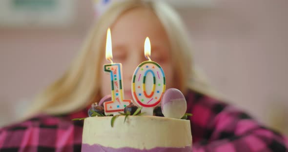 Close Up of Little Girl Blowing Out Color Candles with Number 10 on Birthday Cake in Slow Motion