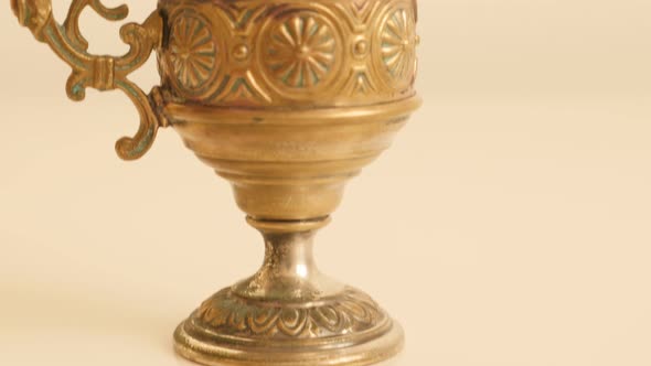 Handmade goblet of brass on white surface 4K 2160p UltraHD tilting footage - Holy grail on white bac