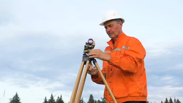 Skilled Surveyor Fixes Dumpy Level on Brown Wooden Tripod