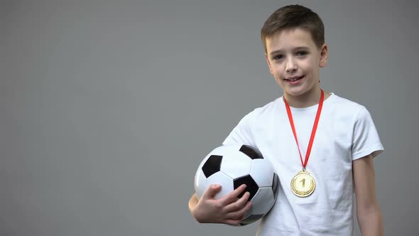 Happy Boy Smiling With Winner Medal on Chest, Holding Soccer Ball, Champion