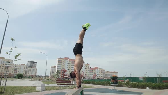 Muscular Young Man Doing a Handstand on the Sports Beam at the City Sports Ground. Circular Movement