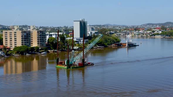 A tug boat manoeuvres a  floating crane up river