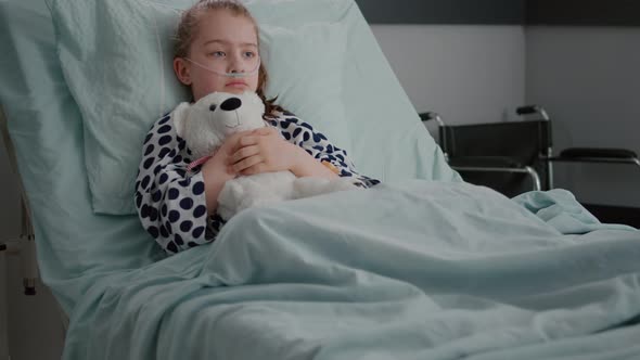 Alone Worried Child Patient Wearing Oxygen Nasal Tube Resting in Bed Holding Teedy Bear