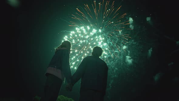 Young Couple Watching Beautiful Fireworks. Silhouette of people watching explosive and colorful fire