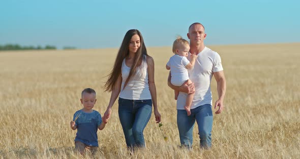 Beautiful Family with Young Children is Walking Through a Wheat Field Vacation in Nature