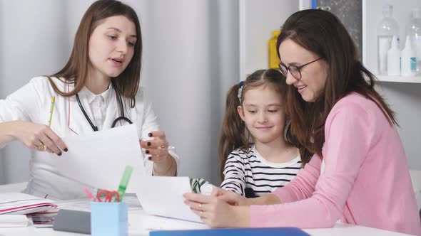 A Woman with a Young Daughter Talking to a Physician Pediatrician in the Office