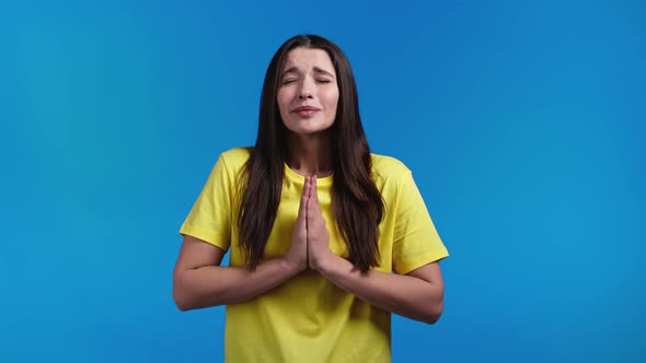 Pretty Woman Praying with Hands on Blue Background