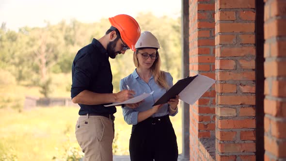 Two Engineer In Helmet Inspecting Building. Civil Architect Checking Construction. Building Project.