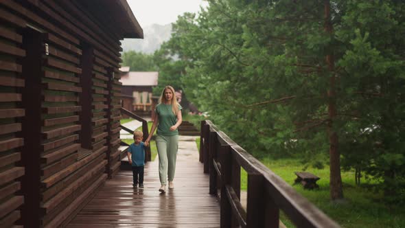 Mother and Little Boy Walk Joining Hands Along Veranda