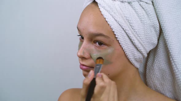 Teenage Girl with Skin Problems Applying Facial Clay Mask at Home Spa