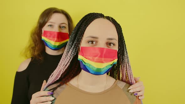 Lesbian Couple in Rainbow Masks on Yellow Background