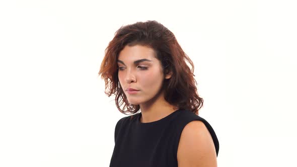 Closeup View of a Depressed Young Woman in Black Dress Looking at the Camera Isolated on White