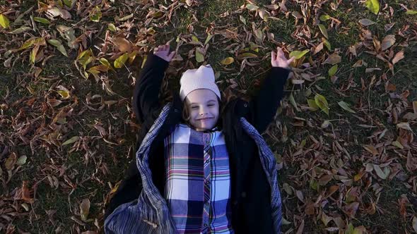 Young Kid Girl Makes Angel Wings in a Autumn Park