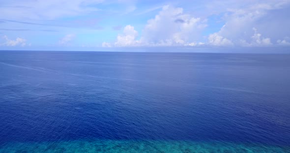 Tropical flying abstract shot of a sandy white paradise beach and blue ocean background in hi res 4K