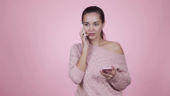 Young Beautiful Woman Manager Takes Turns Talking on Two Smartphones with Clients