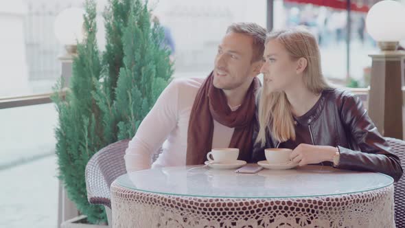 Couple On Date In Street Cafe Drinking Coffee And Communicating