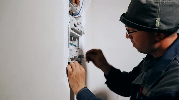 The Master Electrician Connects the Wires to the Circuit Breakers in the Electrical Panel