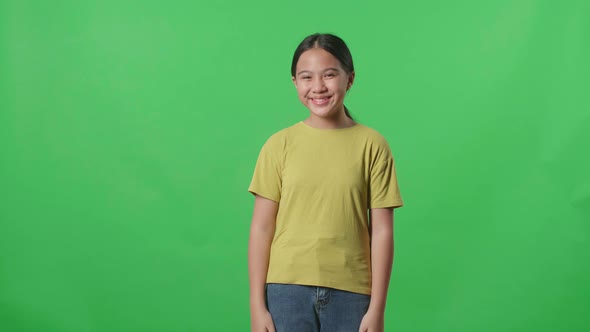 Young Asian Kid Girl Warmly Smiling On Green Screen Background In The Studio