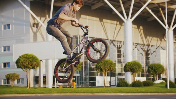 Young Man Bmx Rider in Casual Outfit is Bouncing on His Bike Doing Tricks While Exercising on