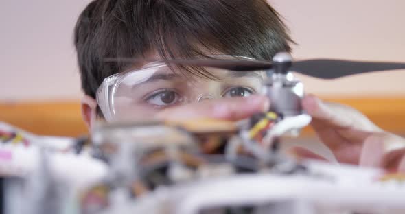A Boy Wearing Goggles Installs a Propeller on a Disassembled Drone