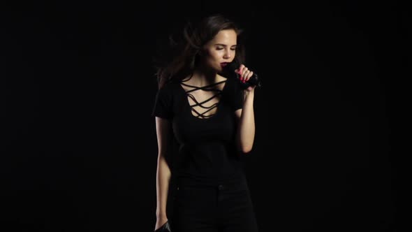 Singer Sexually Dances and Sings Songs in a Microphone at a Concert. Black Background. Slow Motion